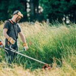 Uomo che taglia l'erba con un decespugliatore per pulizie primaverili