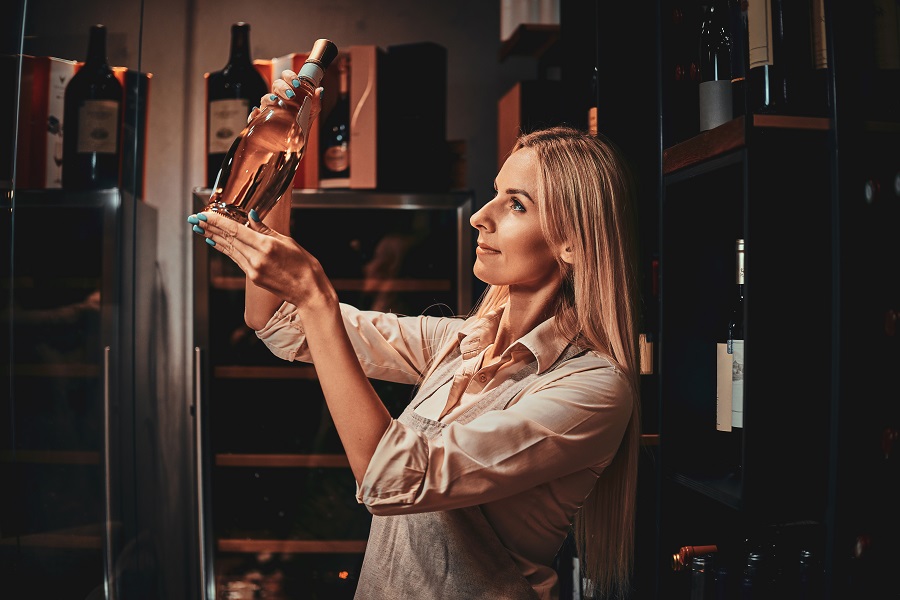 la-bella-donna-concentrata-sta-scegliendo-il-vino-giusto-per-i-clienti-in-una-cantina-scura