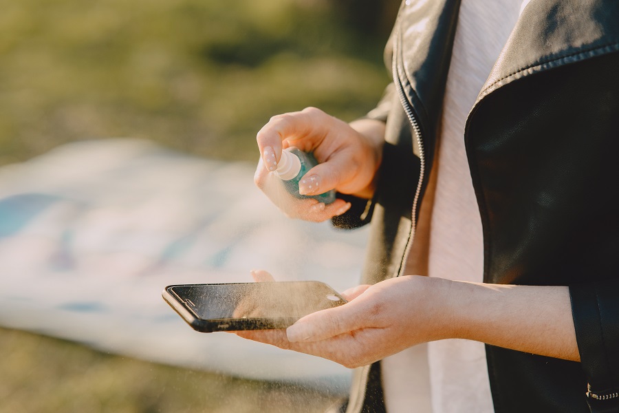 donna che pulisce lo smartphone con disinfettante